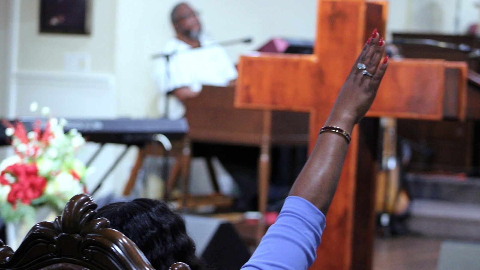 A hand raised in worship beside the cross